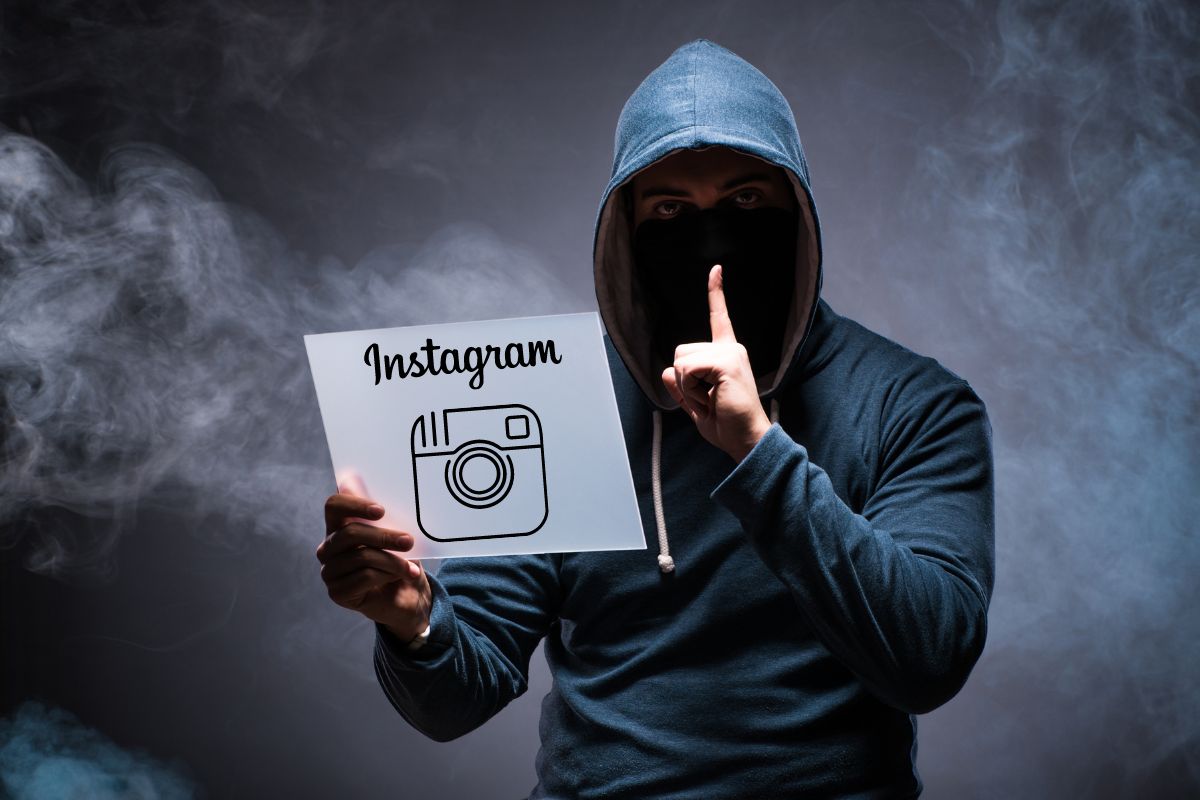 hombre encapuchado con un cartel en su mano rodeado de humo link para hackear instagram